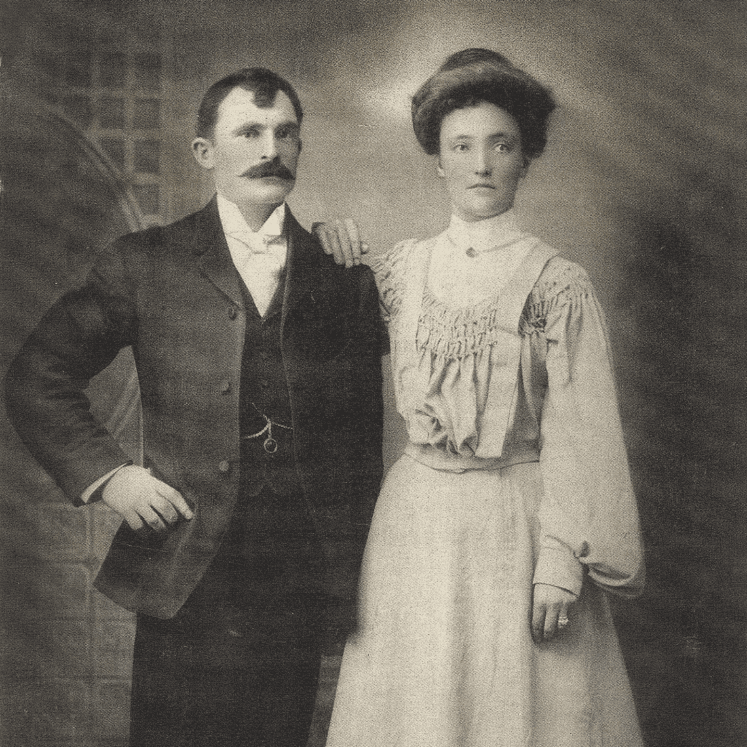 Black and white photo of a husband in a black suite and his wife in a white dress